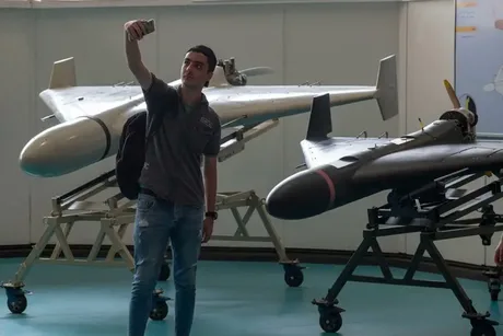 Tânăr fotografiind dronele Shahed într-un spațiu expozițional.