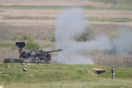 Sistem de apărare aeriană în acțiune, cu fum și activitate militară vizibilă.