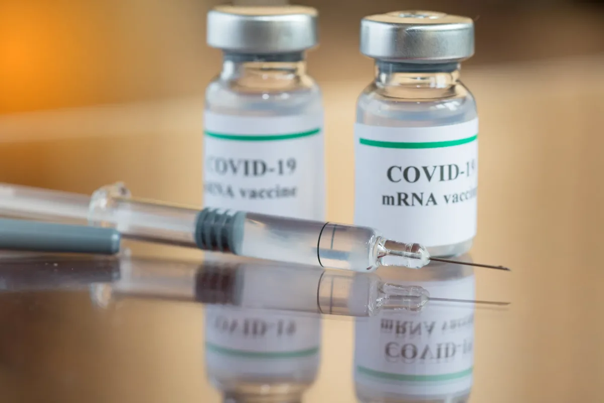 Flacoane de vaccin COVID-19 și o seringă pe masă.