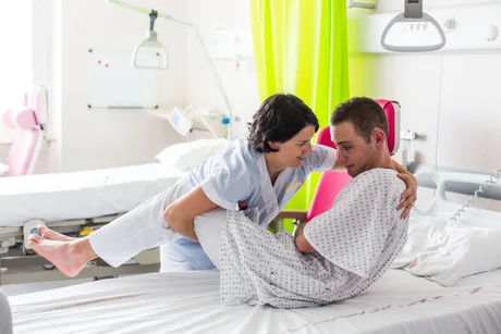 Îngrijitor oferind suport unui pacient într-un spital modern.