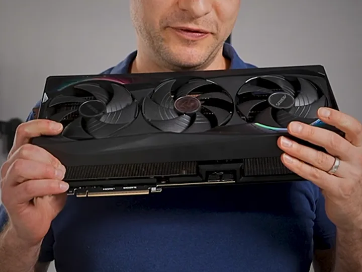 Un bărbat ține o placă grafică Nvidia RTX 5090 în mână, zâmbind.