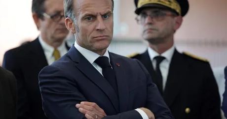 Emmanuel Macron la o ceremonie oficială, cu o expresie serioasă.