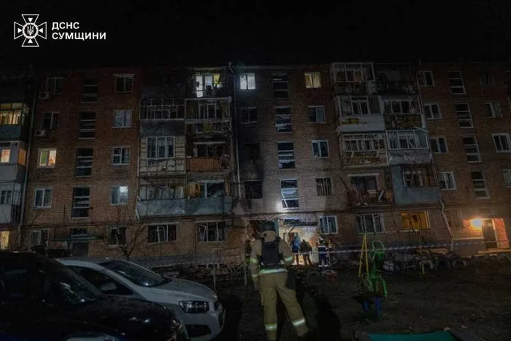 Clădire avariată după atacuri cu drone în Ucraina, cu echipaje de intervenție la fața locului.