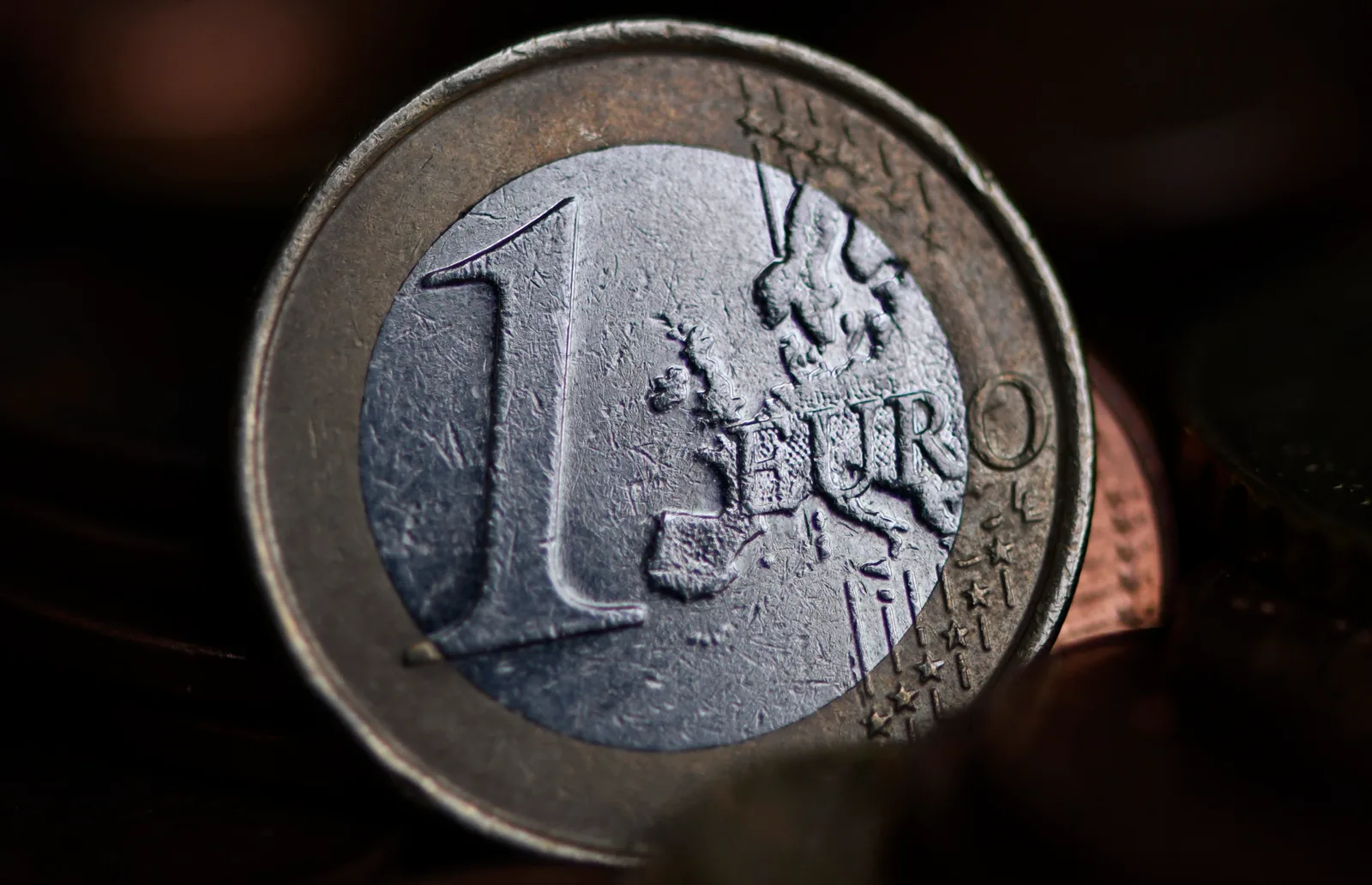 Monedă euro pe fundal întunecat, simbolizând tranziția economică.