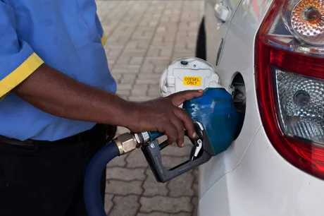 Un bărbat umple rezervorul unei mașini cu motorină la o stație de alimentare.