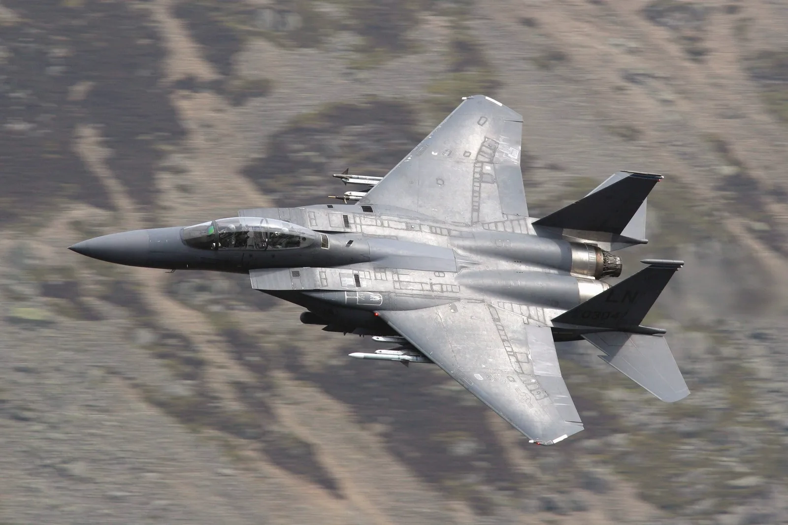 Avion militar zburând deasupra unui peisaj montan impresionant.