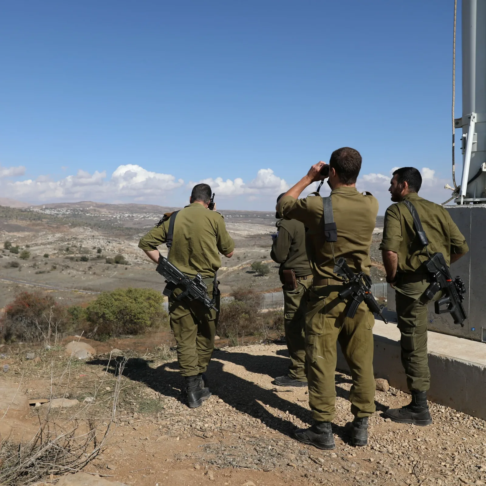 Soldați israelieni observând peisajul din apropierea unei zone de conflict.