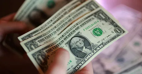 Bancnote de dolar american în mână, simbol al economiei globale.