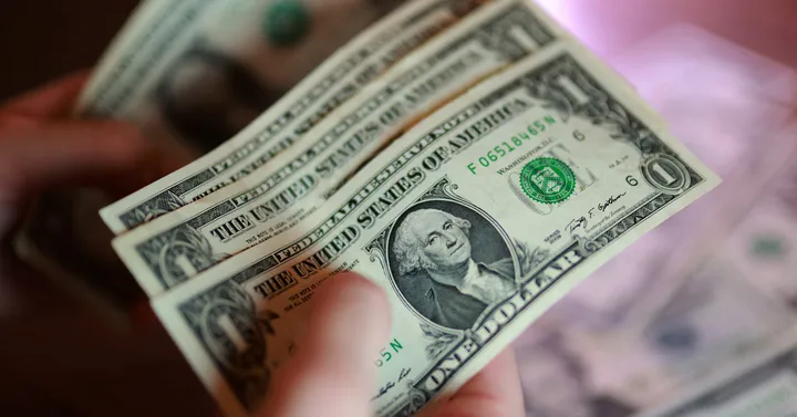 Bancnote de dolar american în mână, simbol al economiei globale.