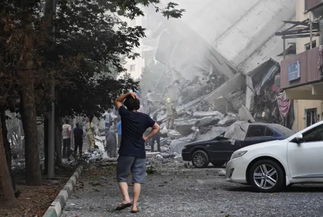 O persoană observă distrugerea unui imobil după un atac aerian devastator.