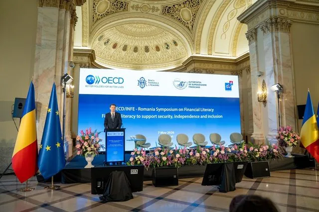 Simpozion dedicat educației financiare, cu steaguri și decor floral elegant.