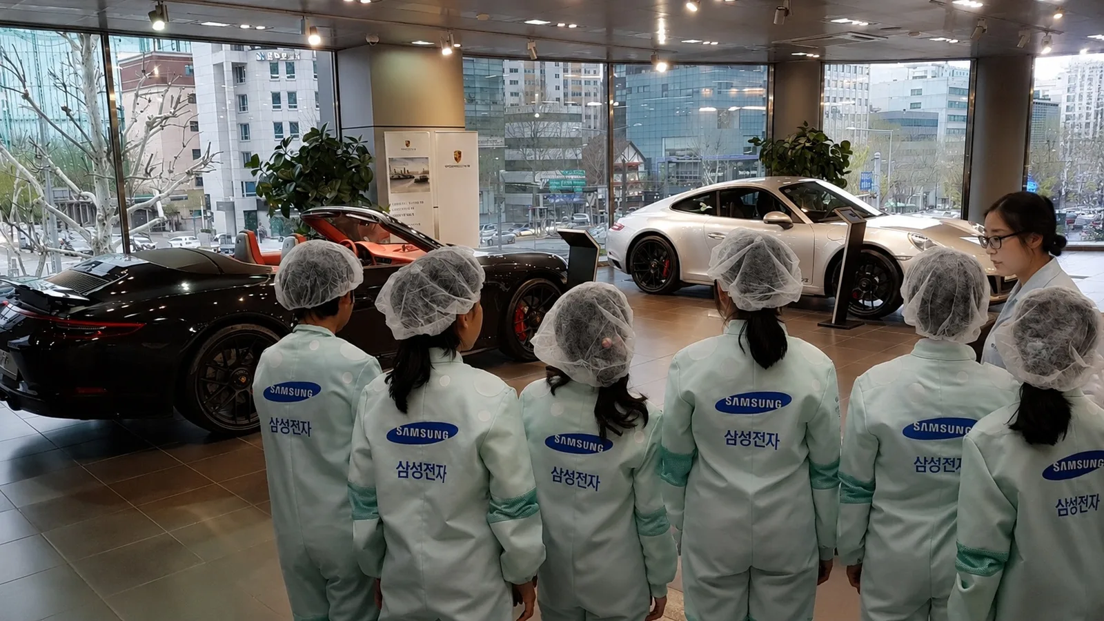 Angajați Samsung admirând mașini de lux într-un showroom Porsche.