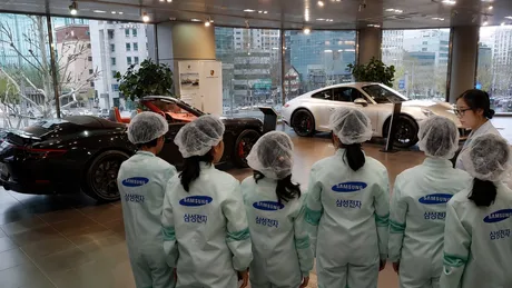 Angajați Samsung admirând mașini de lux într-un showroom Porsche.