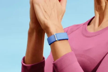 Brățară de fitness Fitbit Air purtată pe încheietura mâinii.