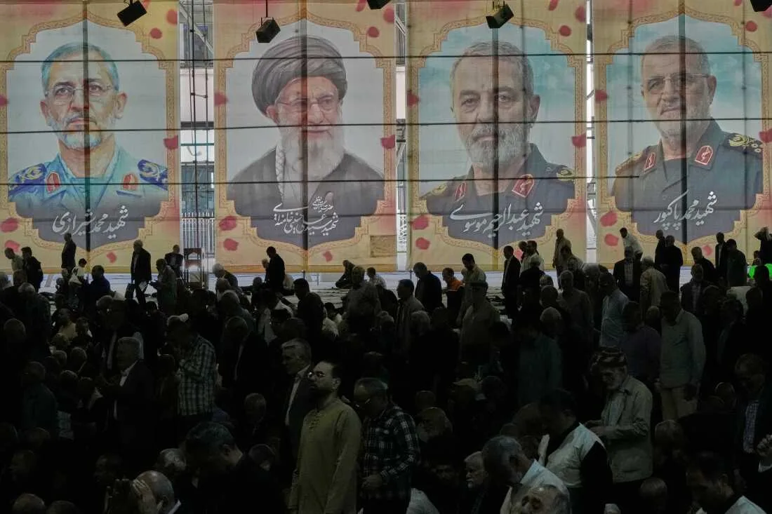 Oamenii se adună sub portrete ale liderilor iranieni într-un eveniment public.