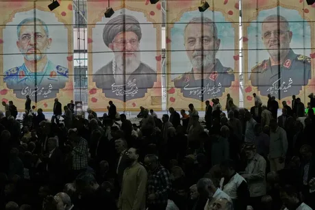 Oamenii se adună sub portrete ale liderilor iranieni într-un eveniment public.