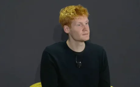 Un bărbat cu păr roșcat, îmbrăcat în negru, ascultând atent.