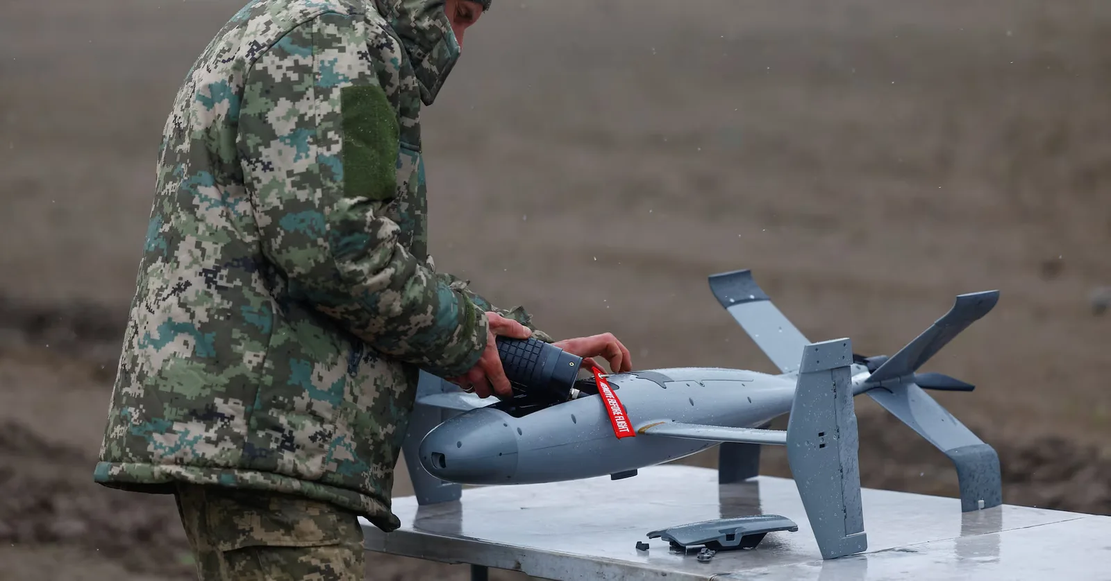 Un soldat pregătește un dron în condiții de vreme nefavorabilă.