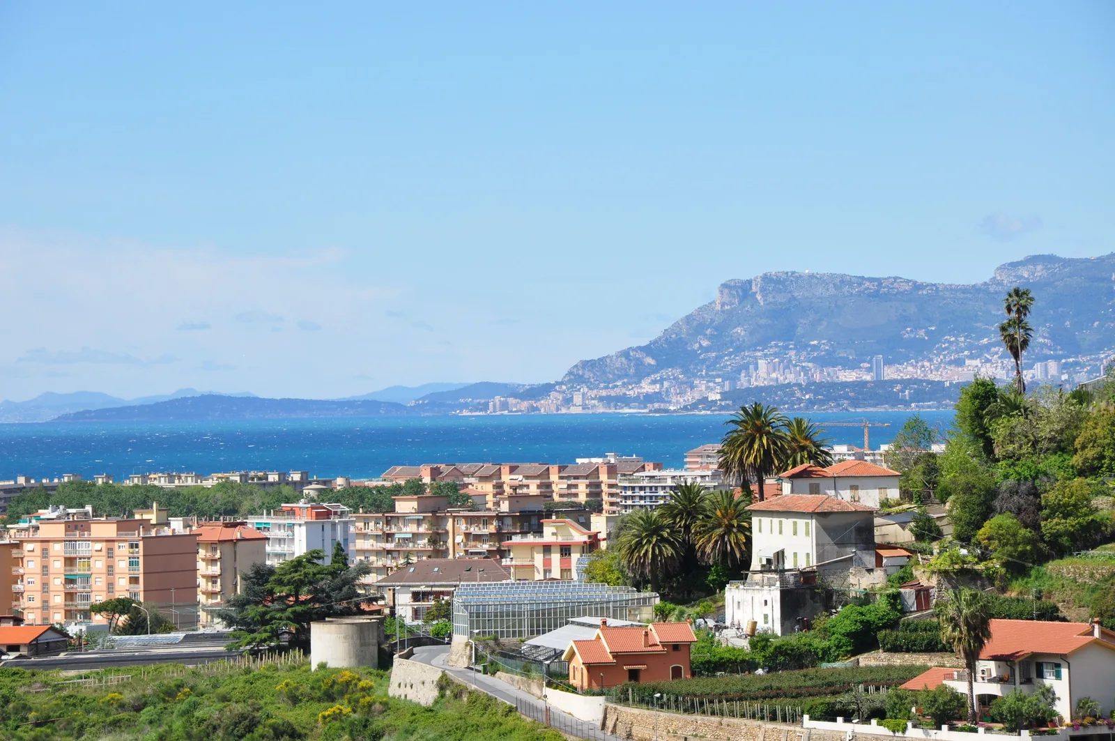 Peisaj din Vallecrosia, cu marea și clădiri pe fundal.