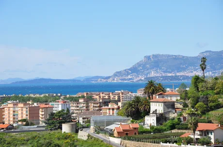 Peisaj din Vallecrosia, cu marea și clădiri pe fundal.