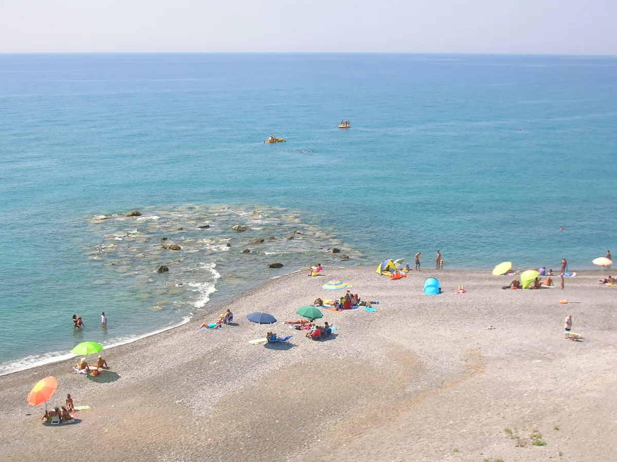Plajă din Vallecrosia, turiști relaxându-se sub umbrele colorate.