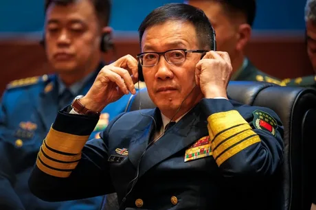 Oficial chinez în uniformă, ascultând cu atenție în timpul unei întâlniri.