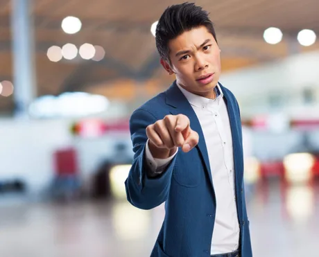 Un bărbat îmbrăcat elegant, arătând cu degetul, exprimându-și nemulțumirea.
