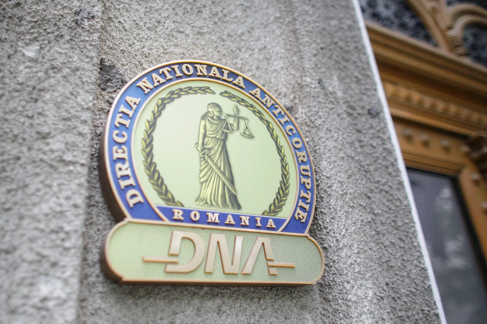 Sigla Direcției Naționale Anticorupție pe un zid, simbol al luptei împotriva corupției.