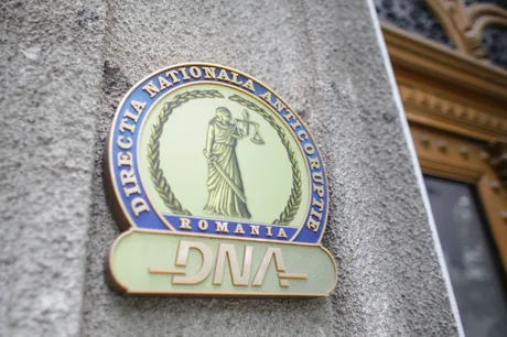 Sigla Direcției Naționale Anticorupție pe un zid, simbol al luptei împotriva corupției.