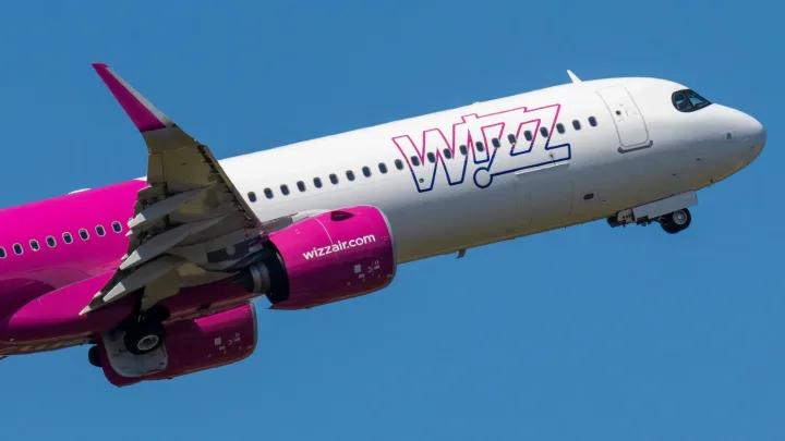 Avion Wizz Air în zbor, pe un cer senin, simbolizând tarifele reduse.