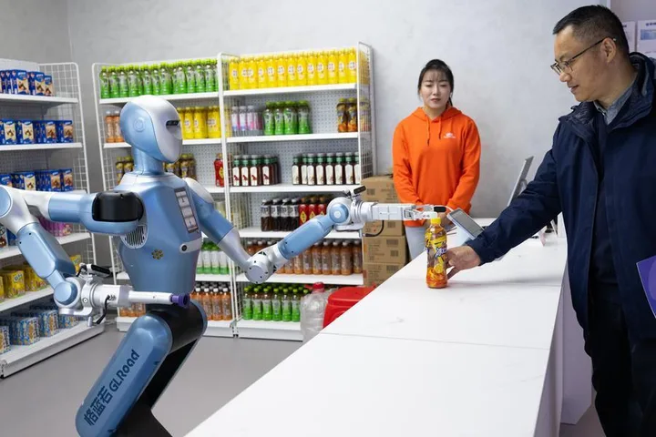 Un robot humanoid interacționează cu un client într-un magazin modern din Wuhan.