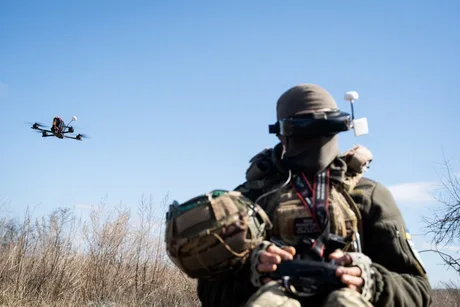 Un soldat controlează o dronă pe câmpul de luptă, evidențiind tehnologia modernă.