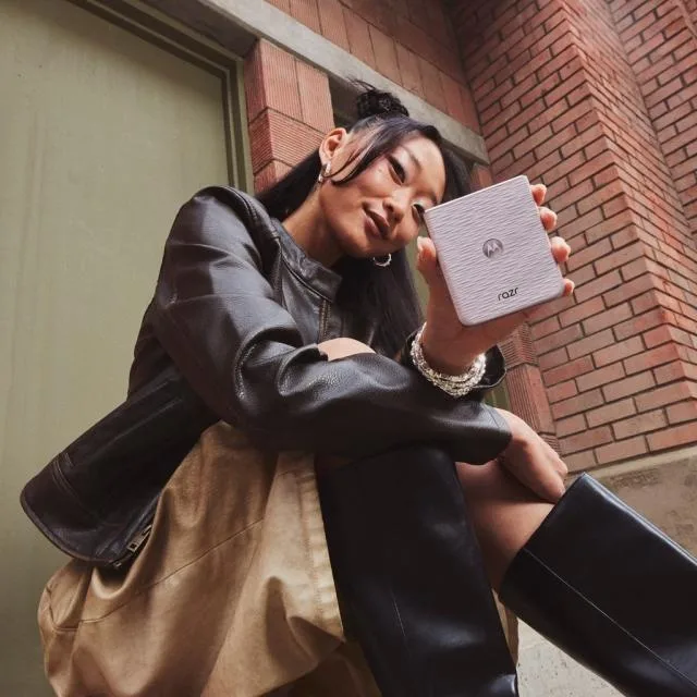 Un tânăr ținând un telefon pliabil Motorola razr 70 în mână.