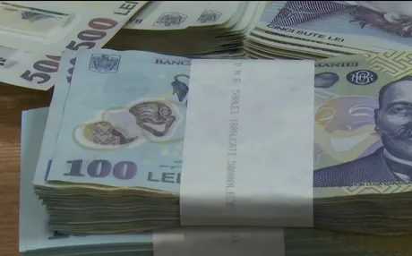 Bancnote românești aranjate pe o masă, simbolizând ajutoarele sociale.