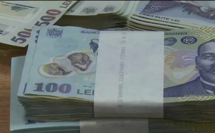 Bancnote românești aranjate pe o masă, simbolizând ajutoarele sociale.