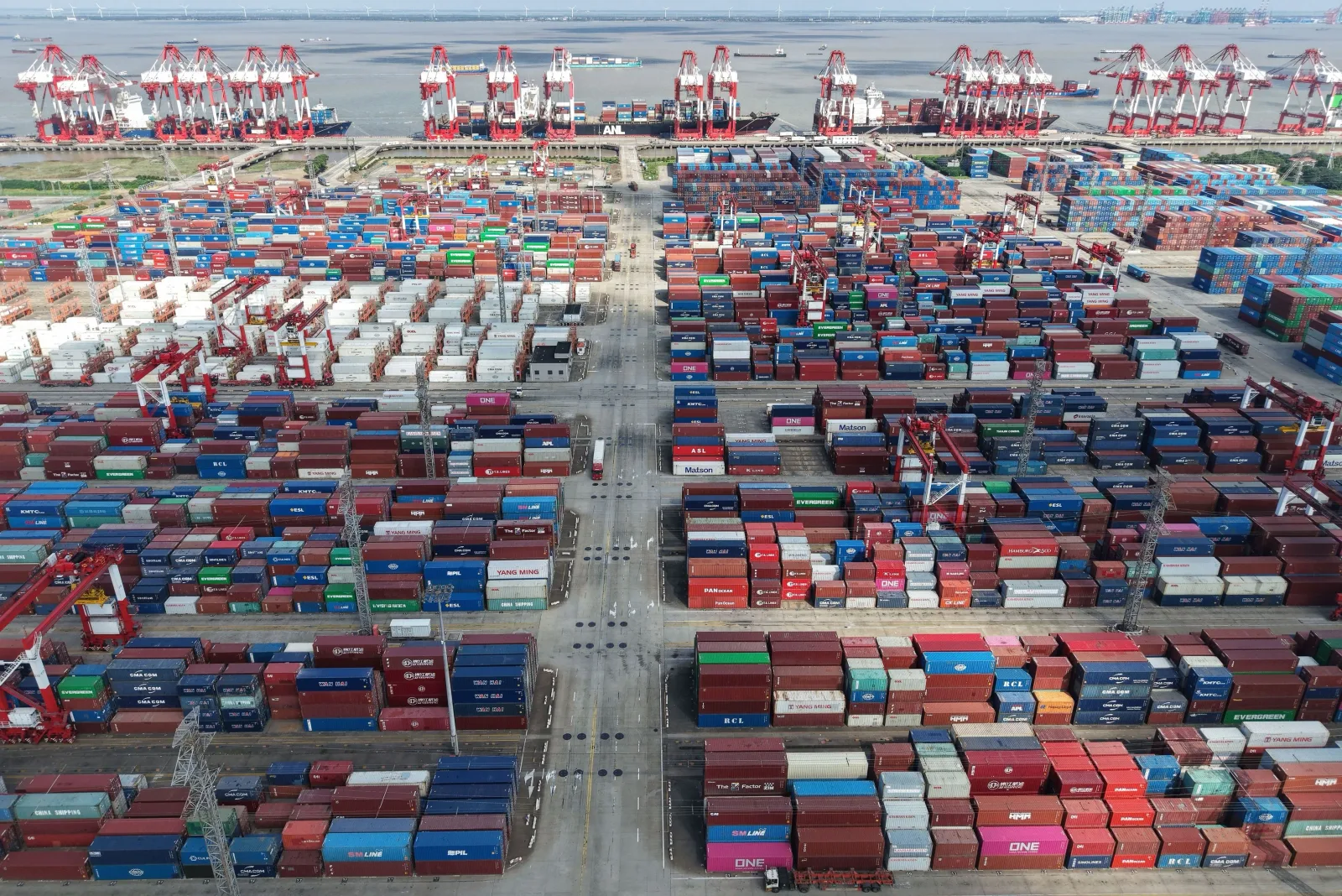 Vedere aeriană a unui port aglomerat cu containere și macarale.