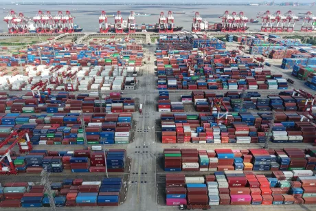 Vedere aeriană a unui port aglomerat cu containere și macarale.