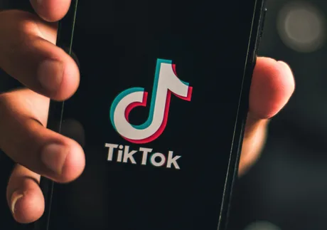 Logo-ul TikTok pe un telefon mobil, simbolizând impactul economic.