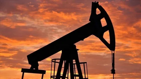 O pompă de petrol silhouetată pe un fundal de apus spectaculos.