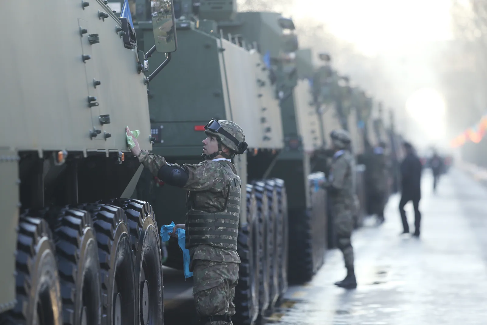 Soldați inspectând vehicule militare în cadrul unei parade.