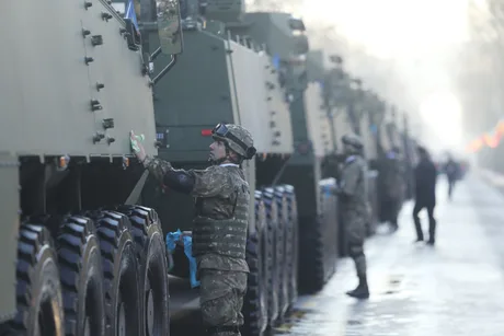 Soldați inspectând vehicule militare în cadrul unei parade.