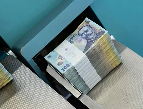 Bancnote românești aranjate pe un suport, simbolizând finanțele.
