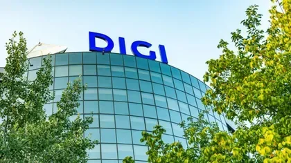 Clădirea Digi cu logo-ul vizibil pe fațadă, înconjurată de copaci verzi.