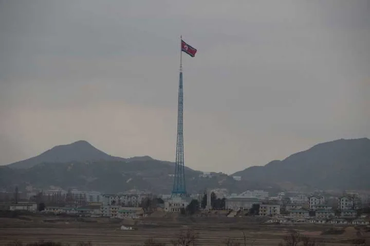 Steagul Coreei de Nord fluturând pe un stâlp în oraș.