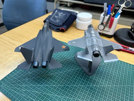 Modele de avioane de luptă J-35 și F-35 pe o masă de lucru.