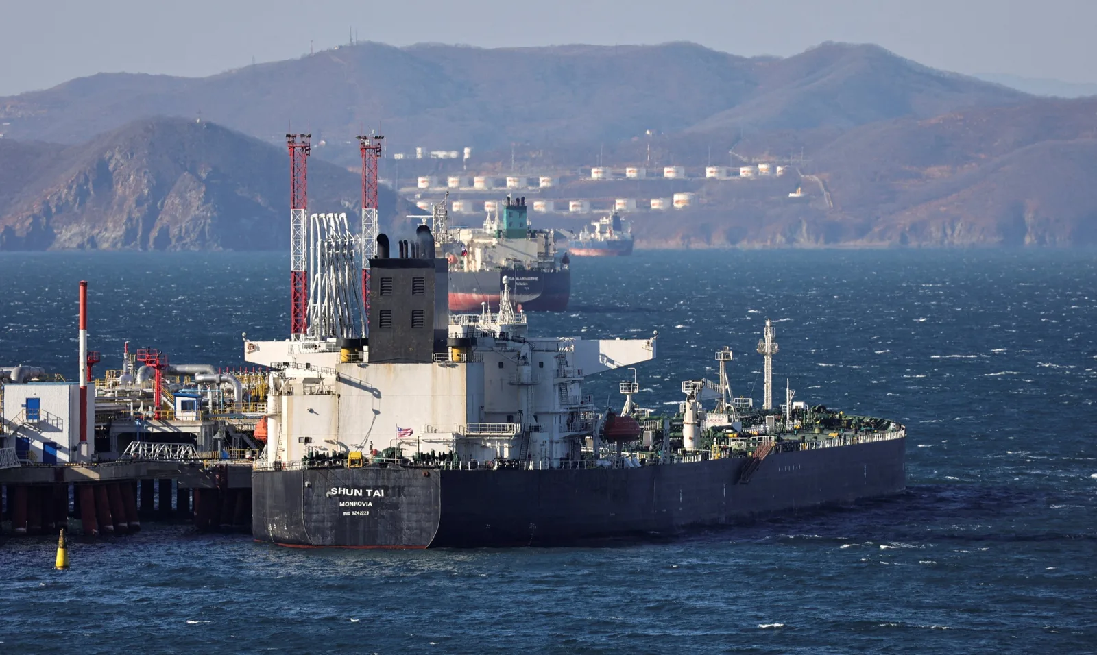 Nave de transport petrol în port, pe fundal montan.