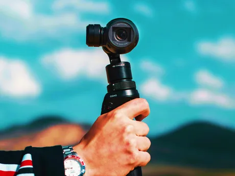 Un utilizator ține un gimbal DJI Osmo Pocket 4 în aer liber.