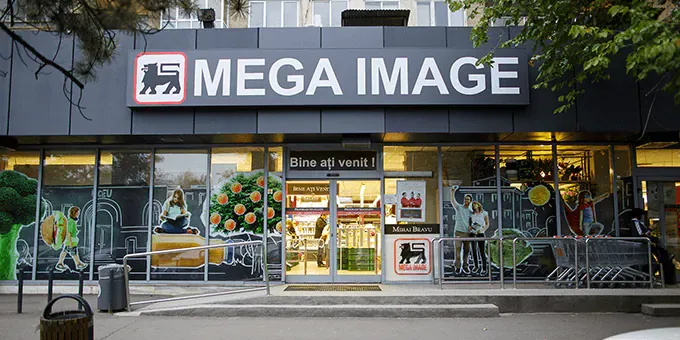 Magazin Mega Image cu produse variate și clienți la intrare.