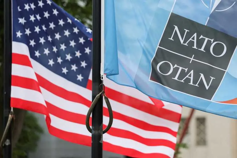 Steagurile NATO și ale Statelor Unite fluturând împreună într-o locație oficială.