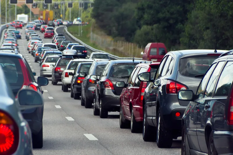 Trafic intens pe o autostradă din România, cu multe autoturisme parcate.